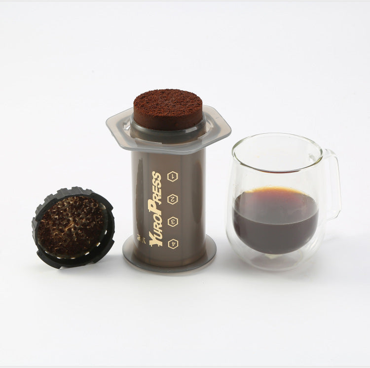Yuro Press coffee maker with two coffee grounds and a glass of coffee on a white background